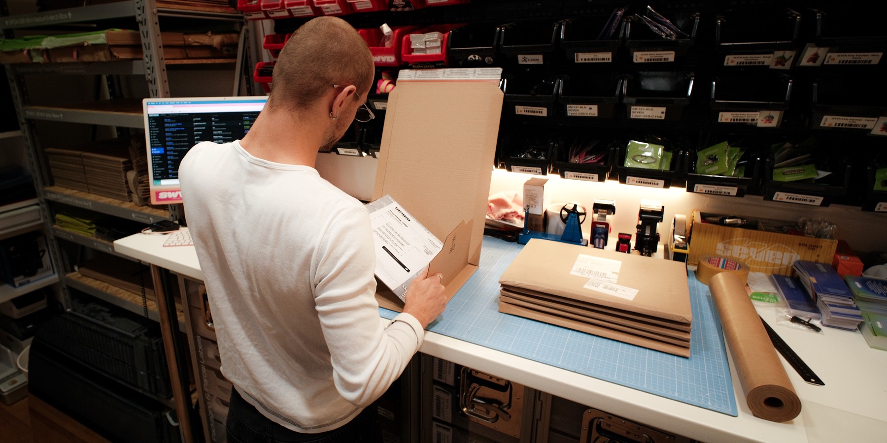 Packing a vinyl order at the SEVEN dispatch bench in Berlin, shelves of stock behind